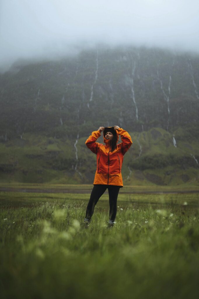 Frau mit orangener Regenjacke im Regen