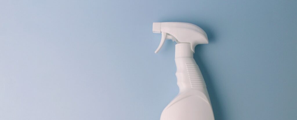 White spray bottle for cleaning on blue background. Minimal cleaning concept