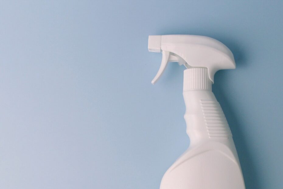 White spray bottle for cleaning on blue background. Minimal cleaning concept